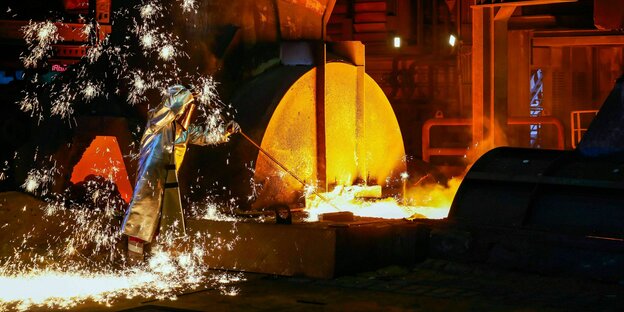 Ein Stahlarbeiter im Schutzanzug entnimmt eine 1500 Grad heisse Roheisenprobe beim Abstich am Hochofen 8 von ThysenKrupp Duisburg