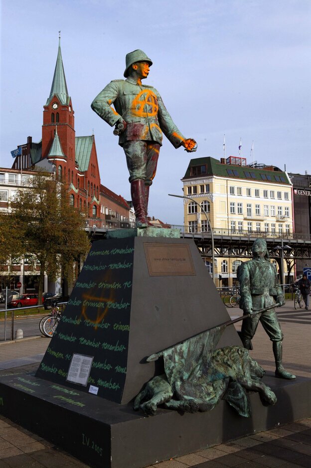 Beschmiertes Denkmal von Hermann von Wismann, ihm zu Füßen kauert ein Löwe, ein einheimischer Soldat schaut zu ihm auf