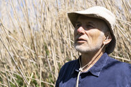 Ein älterer Herr mit grauem Bart und beigem Hut steht vor einem Kornfeld.