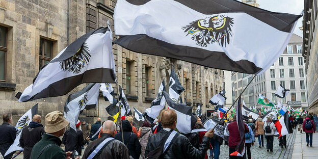 Mehrere hundert Teilnehmer einer Demonstration ziehen mit Flaggen vom Königreich Preußen (schwarz-weiß-schwarz mit Adler) durch die Innenstadt in Dresden.