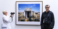 Ausstellung von Wim Wenders. Der Regisseur steht neben einem seiner Fotos.