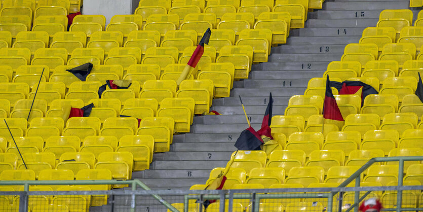 Eine leere Stadiontribüne mit zurückgelassenen Deutschlandfahnen