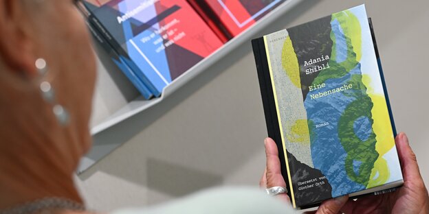 33853933.jpg Eine Mitarbeiterin des Berenberg Verlags Berlin hält am Stand auf der Frankfurter Buchmesse ein Exemplar des Buches «Eine Nebensache» der palästinensischen Autorin Adania Shibli