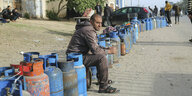 Ein Mann sitzt in einer langen Reihe von Gaszylindern auf der Straße