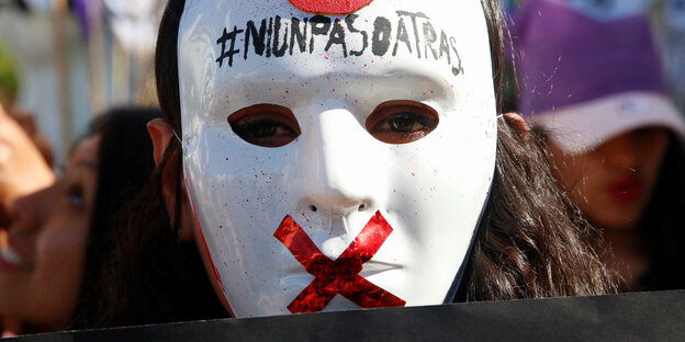 Ein Demonstrant mit einer Maske, auf der "Ni un paso atras" steht