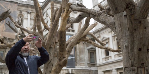 Ai WeiWei in der Royal Academy of Arts. Er knipst ein Foto mit einem Handy.