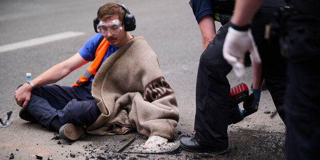 Aktivist hat seine Hand auf den Asphalt einer Straße geklebt