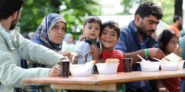 Flüchtlinge sitzen an einem Tisch