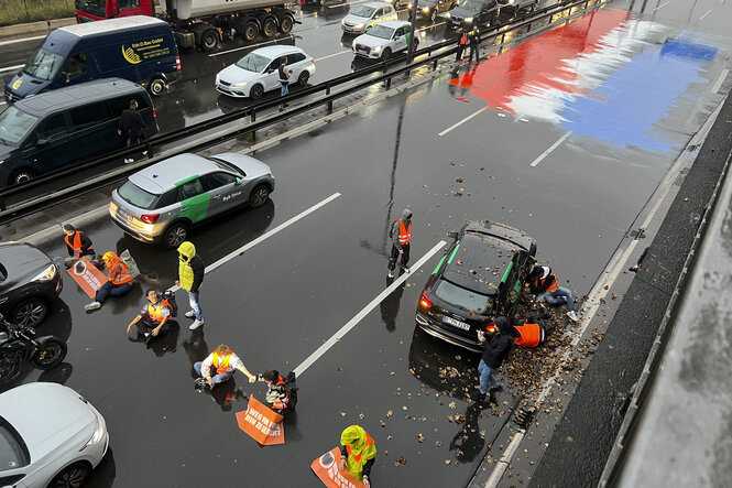 Auf der Straße mit Farbe aufgetragen die niederländische Fahne, Sitzblockade der Letzten Generation