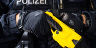 Eine Nahaufnahme eines Polizisten mit einem gelben Taser in den Händen