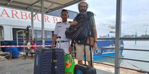 Grimalda mit uniformierter Person hinter Koffern auf indonesischer Fähre