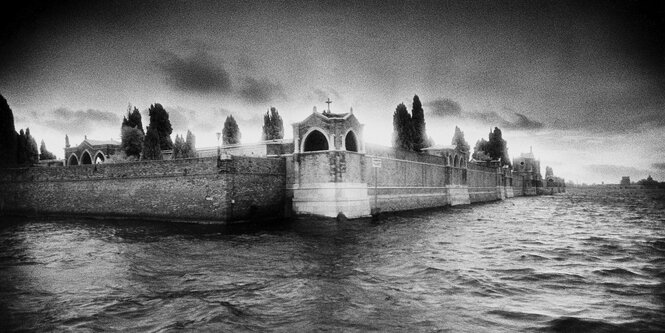 unscharfe schwarz-weiss Aufnahme der Insel San Michele, das Meer ist rauh, dunkel Wolken am Himmel, düstere Stimmung