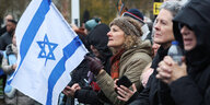 Eine Demonstrantin hält eine israelische Flagge in der Hand, während des Marsches gegen Antisemitismus