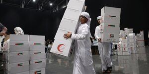 Mitglieder des Roten Halbmonds sammeln Kisten mit Hilfsgütern.