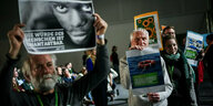 Delegierte beim Bundesparteitag der Grünen halten Plakate zur Migrationspolitik in den Händen