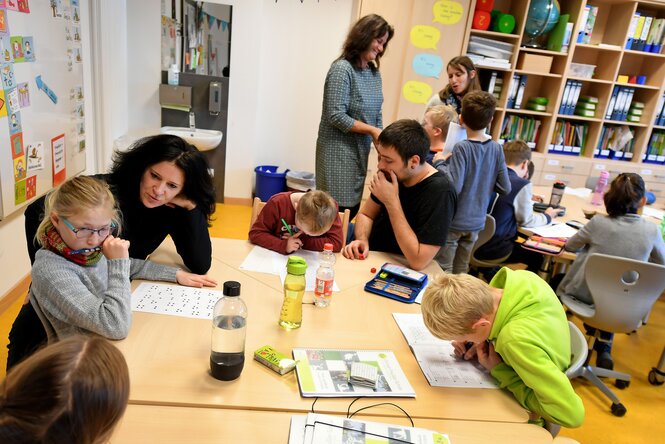 Schüler:innen mit Begleiter:innen in einem Klassenzimmer