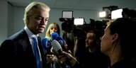 Gert Wilders spricht in ein Mikrofon, umringt von Fernsehkameras