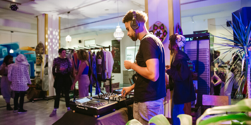 Ein DJ steht im Kulturzentrum Oyoun vor seinem Plattenteller, ein paar Gäste im HIntergrund