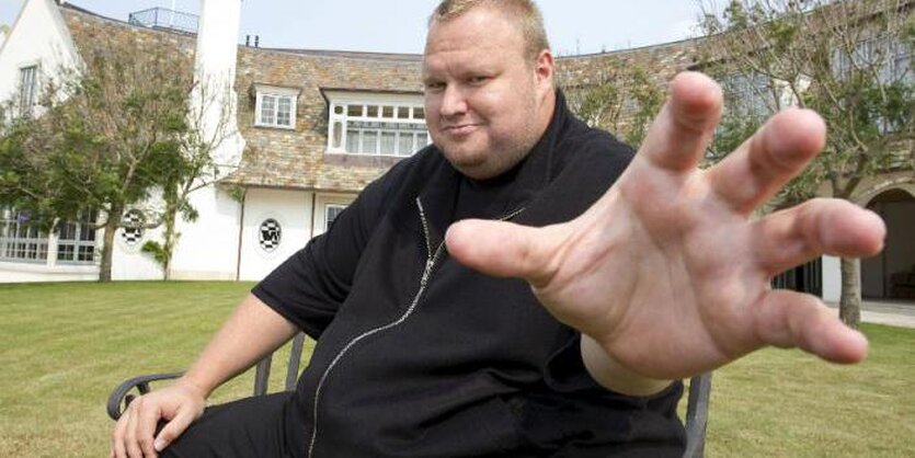 Ein schwarzgekleideter Kim Dotcom greift mit einer Hand Richtung Betrachter