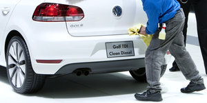 Ein Mann putzt einen VW auf dem steht "Golf TDI Clean Diesel"