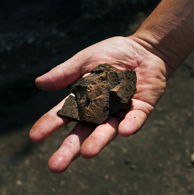 Eine Hand mit einem Stück Braunkohle