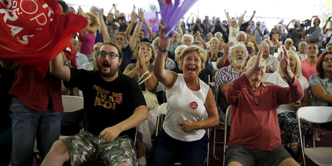 Alexis Tsipras schaut aus einer Wahlkabine.