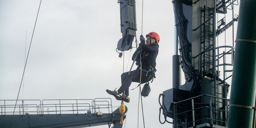 Eine Frau mit Helm hängt an einem Seil.