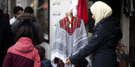 Eine Frau schaut sich ein Palästinensertuch vor einem Geschäft an.