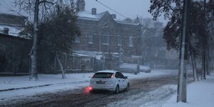 Eine winterliche Straße in Odessa im Dämmelicht ein einzelnes Auto fährt, das rote Rücklich leuchtet