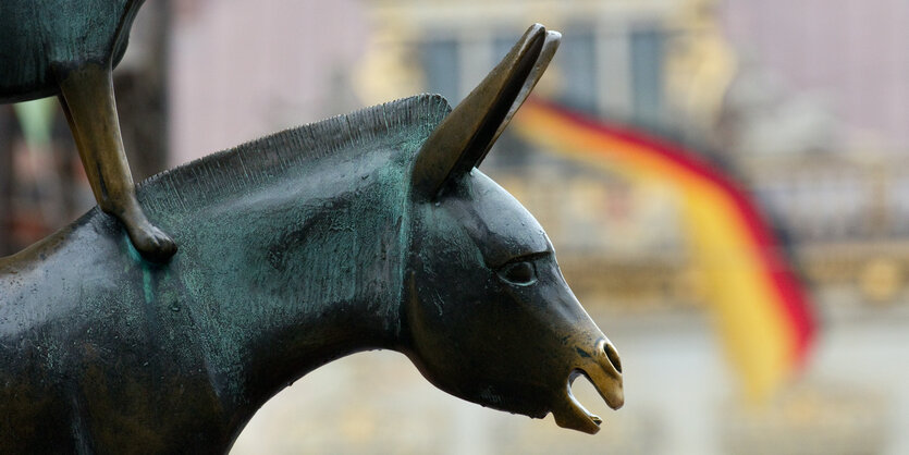 Bremer Stadtmusikanten-Statue vor einer Deutschland-Flagge