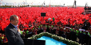Erdogan steht vor Hunderten Menschen mit türkischer Fahne