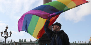 Eine Person schwingt eine große Regenbogenfahne.