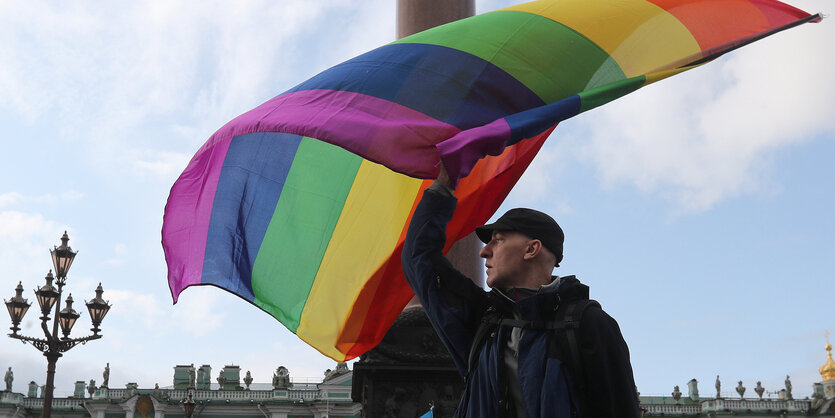 Eine Person schwingt eine große Regenbogenfahne.