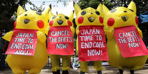 Vier verkleidete Klimaaktivisten protestieren mit Schildern vor dem Bauch