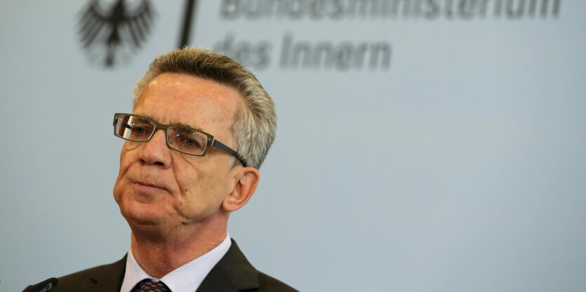 De Maizière vor einem Schriftzug des Bundesinnenministeriums.