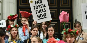 Menschen protestieren, einer hält ein Schild mit der Aufschrift "End Fossile Fuels"