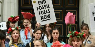 Menschen protestieren, einer hält ein Schild mit der Aufschrift "End Fossile Fuels"