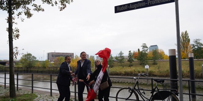 Anna Augstein, Vorstandsvorsitzende der Rudolf Augstein Stiftung, Carsten Brosda (M, SPD), Senator für Kultur und Medien in Hamburg, und Ralf Neubauer (SPD), Bezirksamtsleiter Hamburg-Mitte, enthüllen das Straßenschild «Rudolf-Augstein-Promenade» am «Spiegel»-Hochhaus in der Hafencity.