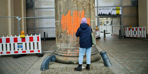 Eine Klimaaktivistin bemalt das Brandenburger Tor mit orangener Farbe