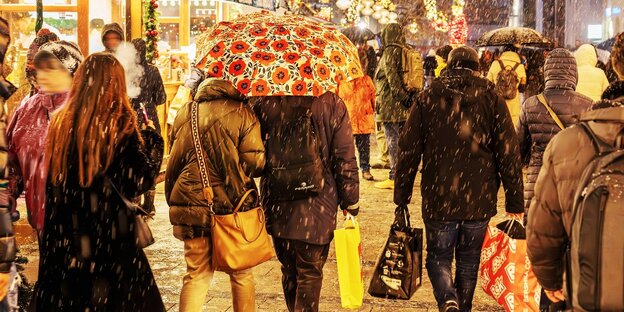 Menschen mit Einkaufstüten in der Münchenr Innenstadt. Es schneit