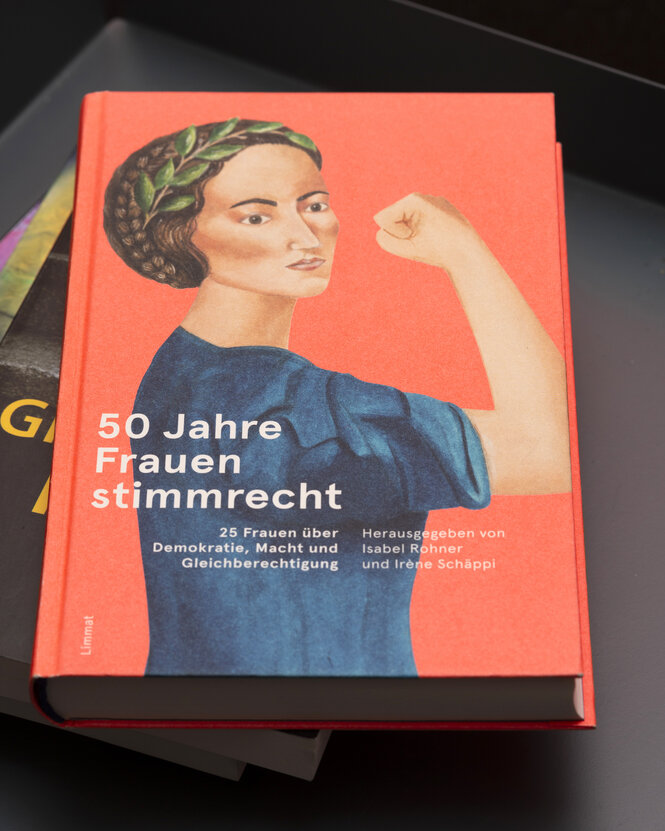 Ein Buch, Titel "50 Jahre Frauenstimmrecht", zu sehen ist eine Frau, die eine Faust ballt