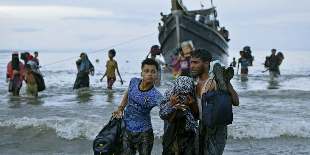 Menschen im Meer, die ein Geflüchtetenboot verlassen