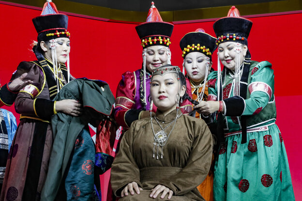 Fünf Menschen in traditionellen Gewändern vor rotem Hintergrund