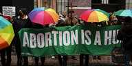 Bunte Regenschirme über einem Banner, auf dem steht "Abortion is a hu..."