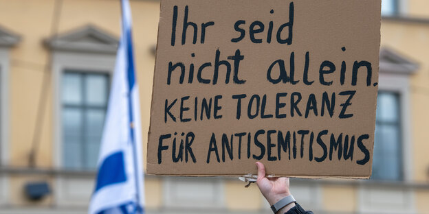 Jemand hält ein Schil mit der Aufschrift "Ihr seid nicht allein, keine Toleranz für Antisemitismus" hoch
