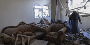 Eine Frau steht verhüllt in einem zerstörten Wohnzimmer