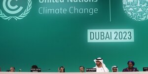 Mehrere Menschen hinter MIkrofonen vor einer Wand mit der Aufschreift "Dubai 2023"