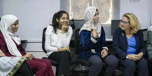 Svenja Schulze sitzt neben Mädchen im Flüchtlingscamp in Jordanien auf einem Sofa
