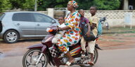 Mutter mit Kindern sitzt auf einem Motorrad, sie sind unterwegs in Sikasso, Südmali