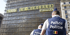 Schriftzug Stop Mercosur- Greenpeace auf der Glasfront des EU-Ministerrats, im Vordergrund 2 Polizisten
